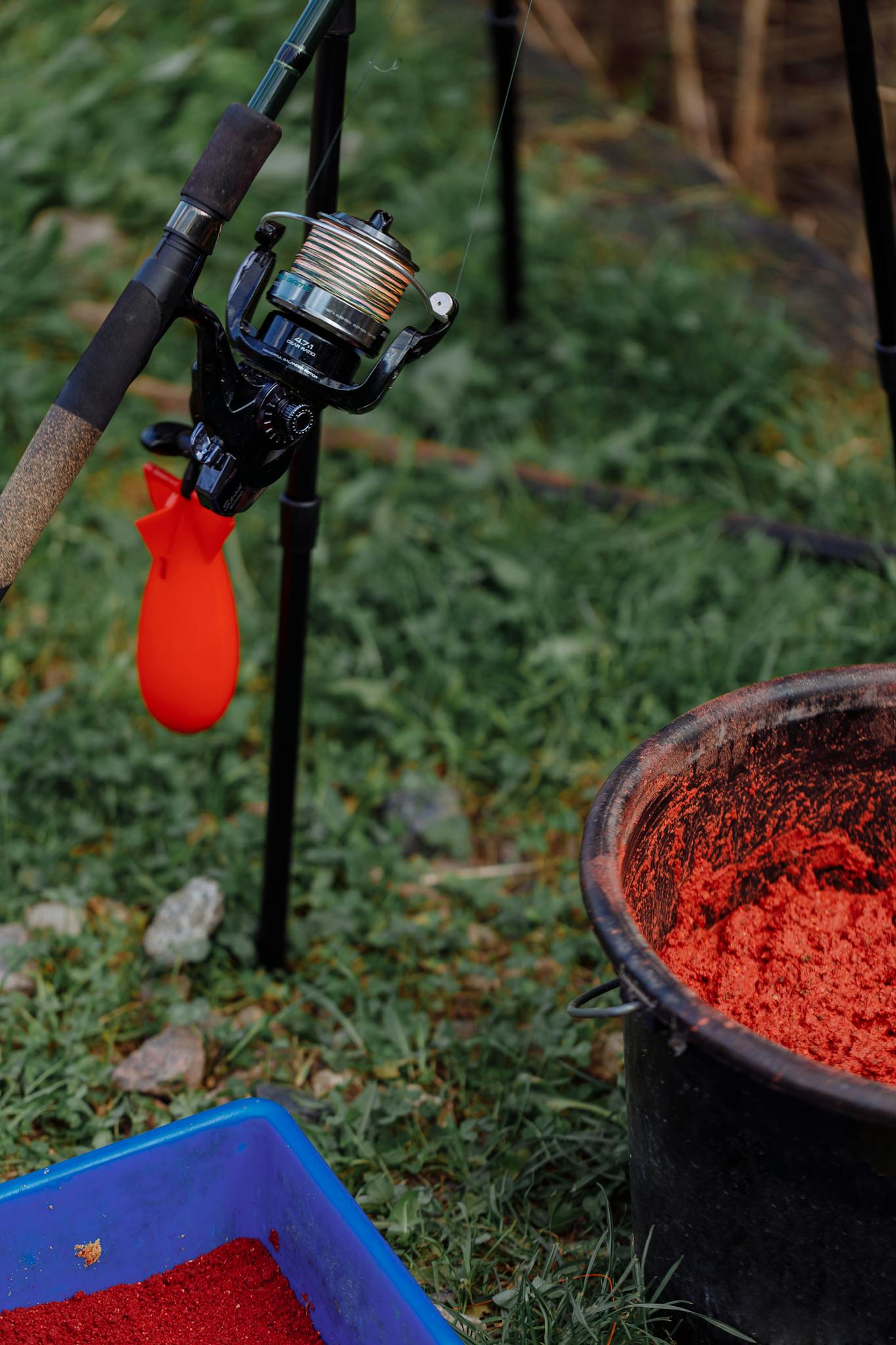 Close-up image of fishing gear with bait on grass, ready for angling outdoors.
