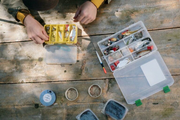 Fishing tools, boxes, and bait displayed on a rustic wooden surface for fishing enthusiasts.