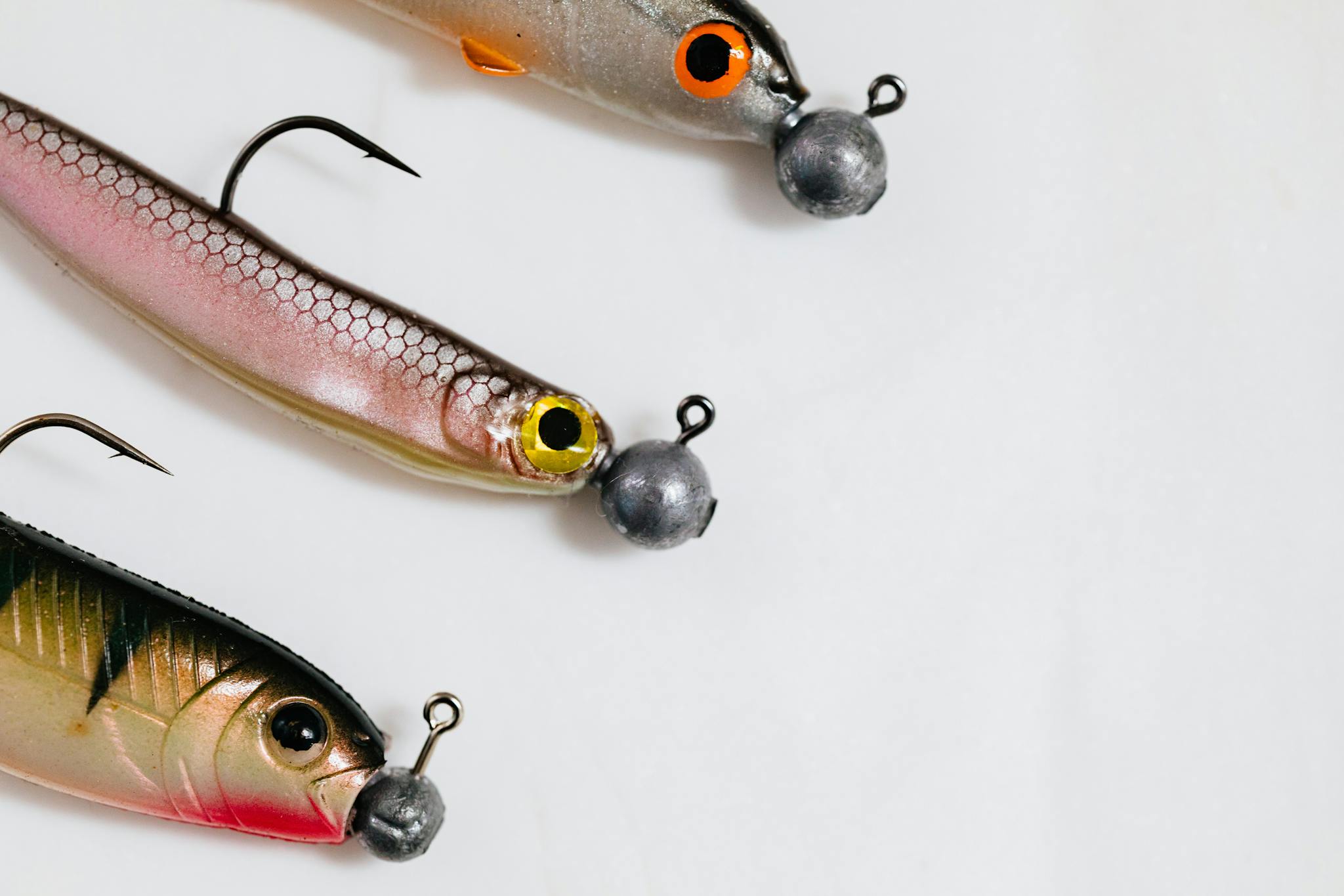Three vibrant fishing lures with hooks on a clean white surface.